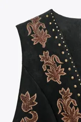 Chaleco marrón de efecto ante con bordados florales y abalorios. Tiene escote en pico, sin mangas y cierre frontal con lazada.