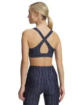 Top deportivo Under Armour con estampado floral en tonos rosa y amarillo sobre fondo negro. Cuenta con tirantes cruzados en la espalda y banda elástica con el logo de la marca en el contorno inferior.