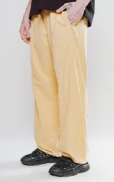 Pantalón de corte sastrero color amarillo claro, de tela suave tipo gamuza, con bolsillos laterales, cintura elástica ajustable y cierre con botón.