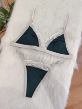 Conjunto de lencería de algodón color verde inglés con detalles de encaje nude, compuesto por un bralette de corte triangular con breteles regulables y una tanga con laterales ajustables.