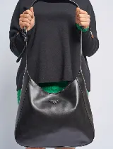 Bandolera tipo hobo de cuero sintético color marrón con correa de hombro ajustable. Tiene un logo triangular metálico en el frente.