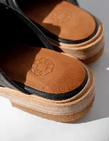Mocasines negros de cuero con hebilla plateada y suela de cuero color natural.