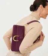 Bolso baguette color borgoña, de cuero sintético, con correa de hombro extraíble y hebilla metálica dorada.