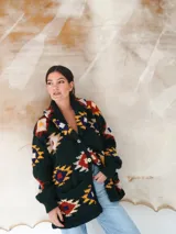 Saco de lana marrón con diseño geométrico multicolor, cuello con solapa, cierre frontal con botones y bolsillos delanteros.