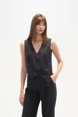 Chaleco de vestir sin mangas, color negro con finas rayas verticales blancas. Presenta escote en V, cierre frontal con botones y bolsillos falsos a la altura de la cintura.