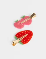 Set de dos hebillas para el pelo con forma de manzana rosa y frutilla roja, con detalles en verde y pinza dorada.