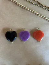 Dije de corazón grande de piedra facetada en colores negro, violeta y naranja, con engarce dorado.