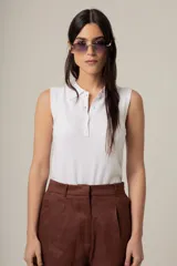Top blanco sin mangas con cuello polo y botonadura frontal parcial.
