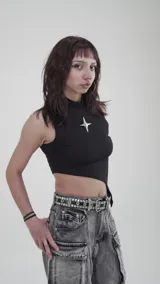 Musculosa negra con cuello alto y corte asimétrico. Presenta un broche removible en forma de estrella plateada.