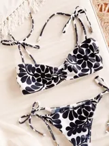 Conjunto de bikini estampado con flores azules y blancas, compuesto por un corpiño con breteles finos que se atan en los hombros y detalle de fruncido en el centro con lazo independiente, y una bombacha clásica.
