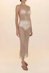 Vestido largo tejido de hilo dorado con diseño calado y flecos en el ruedo.