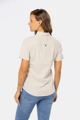 Camisa color beige de lino y algodón, de manga corta, con cuello clásico, medio abotonado y dos bolsillos en el pecho.