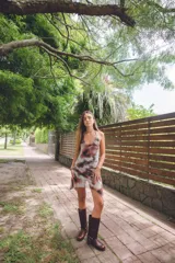 Vestido corto con estampado abstracto en tonos rosados, escote en V y breteles finos que se atan al cuello. Tiene corte en la cadera y falda con ruedo irregular y pico en lateral.