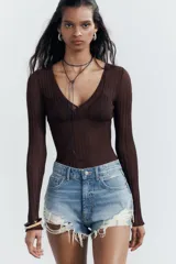 Shorts de denim negro con tiro medio, cinco bolsillos y efecto desgastado con roturas pronunciadas y bajo deshilachado.