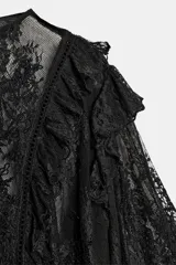 Camisa de encaje negra con cuello redondo y manga tipo capa con volantes.
