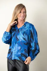 Blusa estampada en tonos de azul, de seda y viscosa, con escote en V y mangas largas terminadas en puño elástico.
