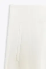 Pantalón capri blanco de tiro alto con bolsillos delanteros de vivo y cierre frontal con cremallera, botón interior y gancho metálico.