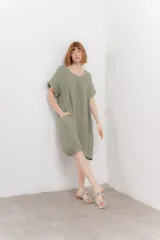 Vestido corto color verde oliva, confeccionado en lino, con corte recto y mangas cortas. Presenta bolsillos laterales y botones decorativos en los laterales.