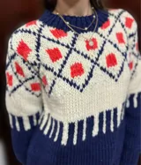 Sweater de lana merino con cuello redondo y diseño con motivos geométricos en tonos azul, marrón, naranja, verde y beige.