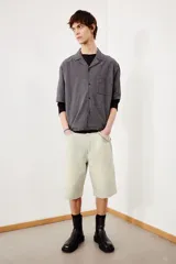 Camisa de manga corta en sirsaca de algodón a rayas grises y negras. Modelo boxy con cuello abierto, tapeta lisa, bolsillo superior y bajo recto. Corte holgado.