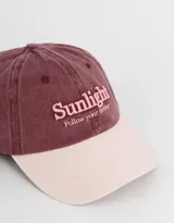 Gorra de gabardina color gris oscuro con visera color beige. Tiene bordado frontal con la palabra "Sunlight" y la frase "Follow your destiny".
