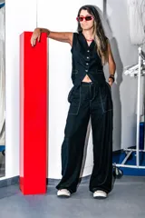 Pantalón negro de lino con tiro medio, elástico en la cintura trasera, bolsillos delanteros carpinteros en contraste blanco y botón marmolado.