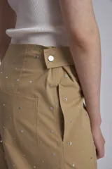 Pantalón color beige con tachas plateadas, tiro alto y corte recto.