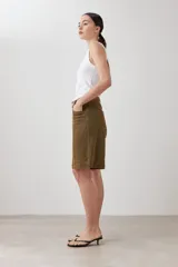 Bermuda de jean color verde oliva, corte a la rodilla, con bolsillos delanteros y traseros, y presillas para cinturón.