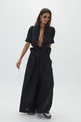 Pantalón negro súper ancho de lino 100% natural, tiro medio-alto, con tablas delanteras, elástico en la parte trasera y bolsillos laterales.