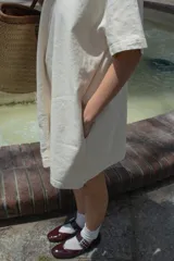 Vestido corto color crudo, de corte amplio en A y mangas cortas. Confeccionado en denim de algodón de bajo impacto ambiental y bolsillos laterales.