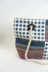 Bolso tipo tote con diseño de bloques de color rosa, rojo y blanco con estampado de lunares y textura tejida. Asas de soga gruesa.