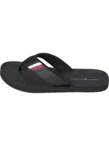 Ojotas negras Tommy Hilfiger con tira ancha de poliuretano acolchada y suela de goma EVA. Detalle de cinta distintiva con los colores de la marca en la tira.