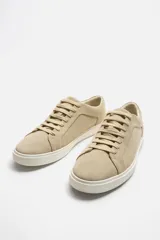 Zapatillas bajas color beige de gamuza, con cordones y suela blanca.