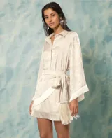 Minifalda color beige con estampado floral, corte recto y detalle de flecos en el ruedo. Incluye cinturón con lazada.