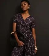 Mono largo de microfibra con estampado geométrico en tonos marrones y blancos. Tiene escote en V, mangas cortas y lazo ajustable en la cintura.