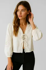 Blusa color crema de algodón con volados, corte holgado, escote en V y lazos para atar.