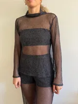 Polera de malla negra con acabado brillante y diseño de cuello alto.