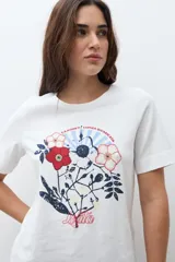 Remera blanca de manga corta con cuello redondo y un estampado frontal de flores y follaje en tonos rojo, azul marino y blanco.