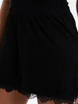 Short de pijama color lila con estampado de flores blancas y ribete de encaje en el ruedo.