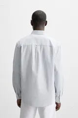 Camisa azul marino de corte regular fit, confeccionada en tejido de algodón Oxford. Tiene cuello abotonado, manga larga con puños abotonados, bolsillo de parche en el pecho y cierre frontal con botones.