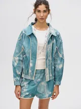 Campera rompevientos estilo biker con capucha desmontable, color celeste con estampado de nubes blancas y detalles en blanco.