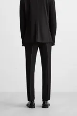 Pantalón de vestir negro slim fit, confeccionado en tejido con viscosa. Cuenta con bolsillos frontales y traseros de vivo. El cierre es frontal con cremallera y botón.