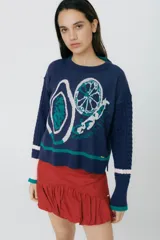 Buzo azul marino tejido en jacquard con diseño de frutas y verduras. Tiene mangas tejidas en ochos, bordado en la espalda y puños con agujerito para el dedo.