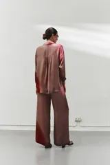 Pantalón largo de pierna ancha color marrón con estampado degradado en tonos rosados y rojizos. Tiene cintura elástica, bolsillos laterales y costuras delanteras y traseras.