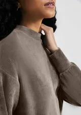 Buzo color beige en tela acanalada con cuello alto y puños ajustados.
