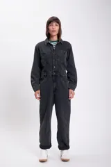 Mono de jean negro con cuello camisero, cierre frontal con botones y bolsillos en el pecho y laterales.