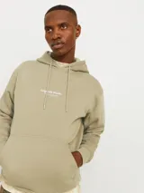 Canguro color beige con capucha, mangas largas, corte relajado y bolsillo tipo canguro. Estampado con texto "Originals Studio" en el pecho.