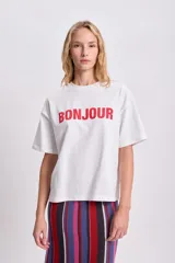 Remera blanca de corte boxy con estampa roja de la palabra "Bonjour".