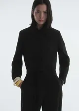 Chaqueta corta negra de mezcla de lana con cuello de solapa, cierre frontal con botones, dos bolsillos laterales y forro interior.