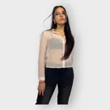 Camisa rosa pálido de tela transparente con textura y pequeños tajos en los costados. Tiene cuello clásico, mangas largas con puños abotonados y cierre frontal con botones.